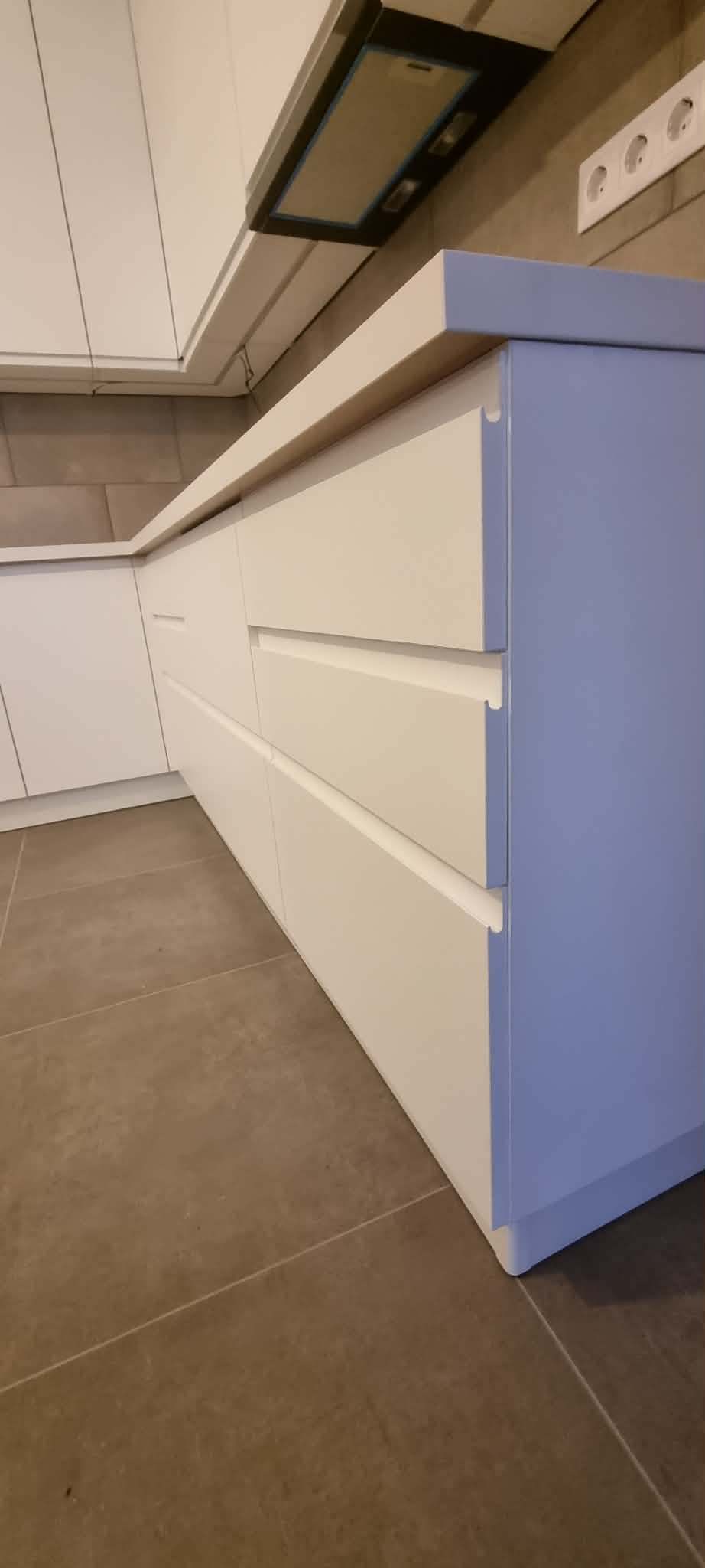 Fehér matt konyhasziget fogantyú nélküli fiókokkal és pasztellkék oldallappal