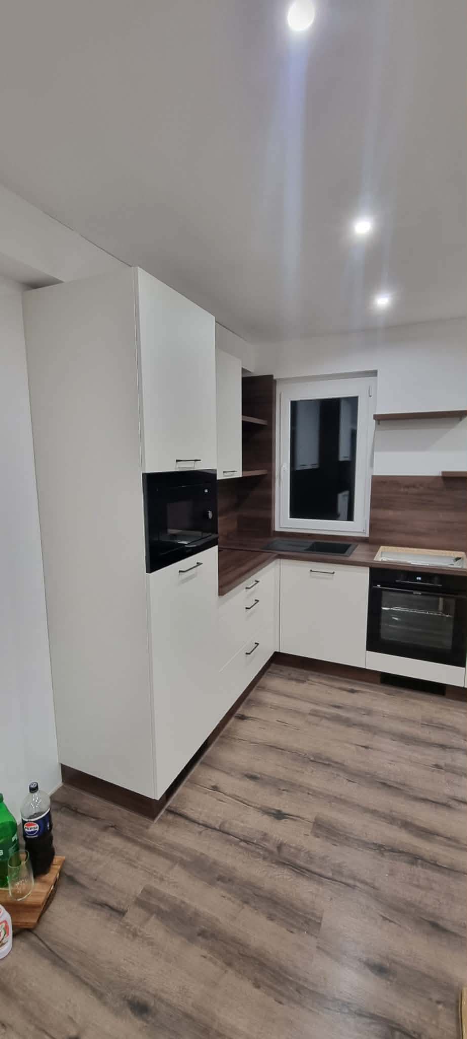 Fehér magasfényű konyhabútor beépített mikróval, sütővel és sötét dió hátfallal